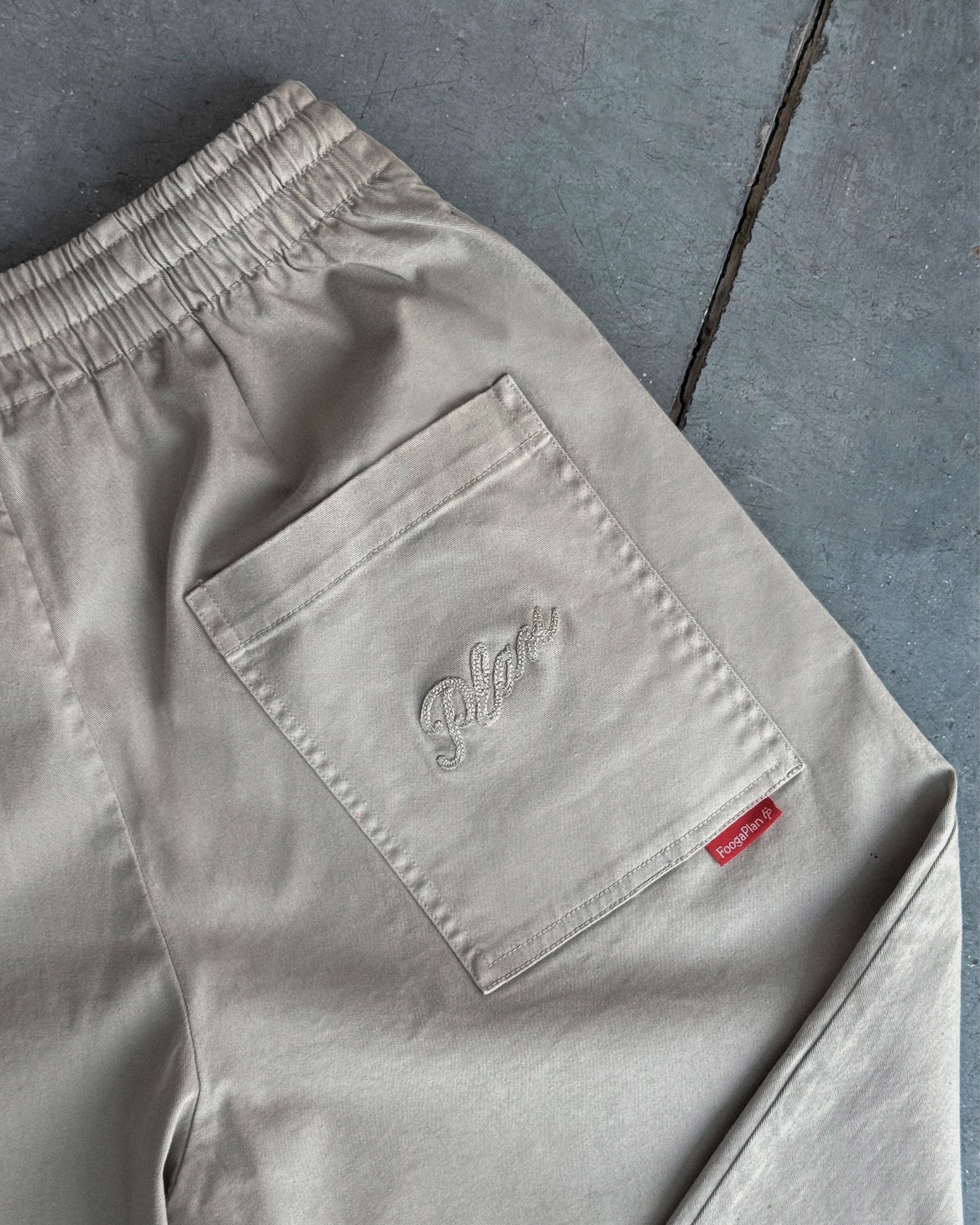 pantalón chino origami khaki pants. color beige. cintura elástica con cordón ajustable. bolsillo bordado vista detalle etiqueta trasera 